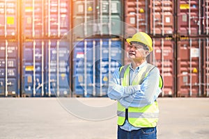 Portrait ofÂ Logistic engineer worker man standing in shipping container yard and crossed arms. Confident engineering work at